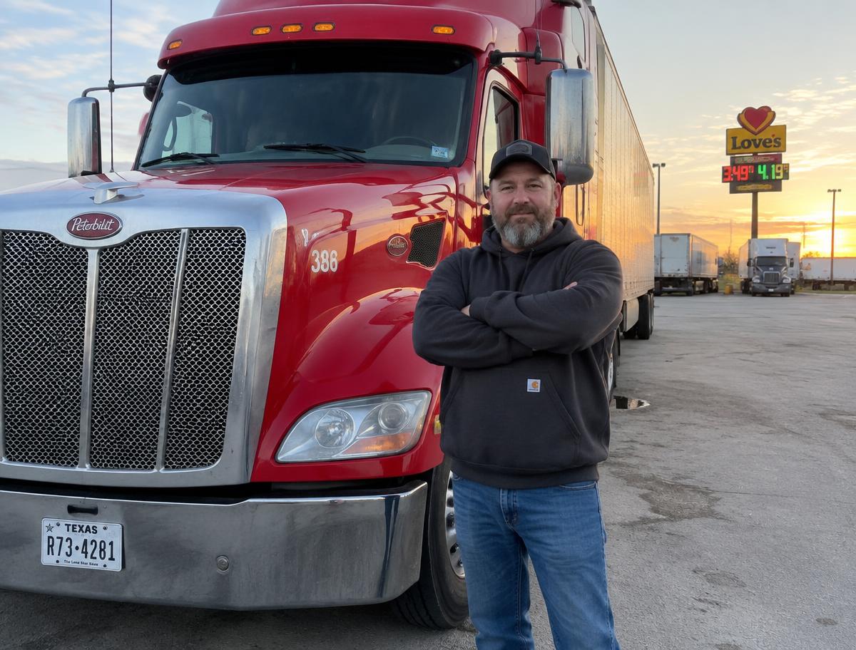 An owner-operator standing beside his truck